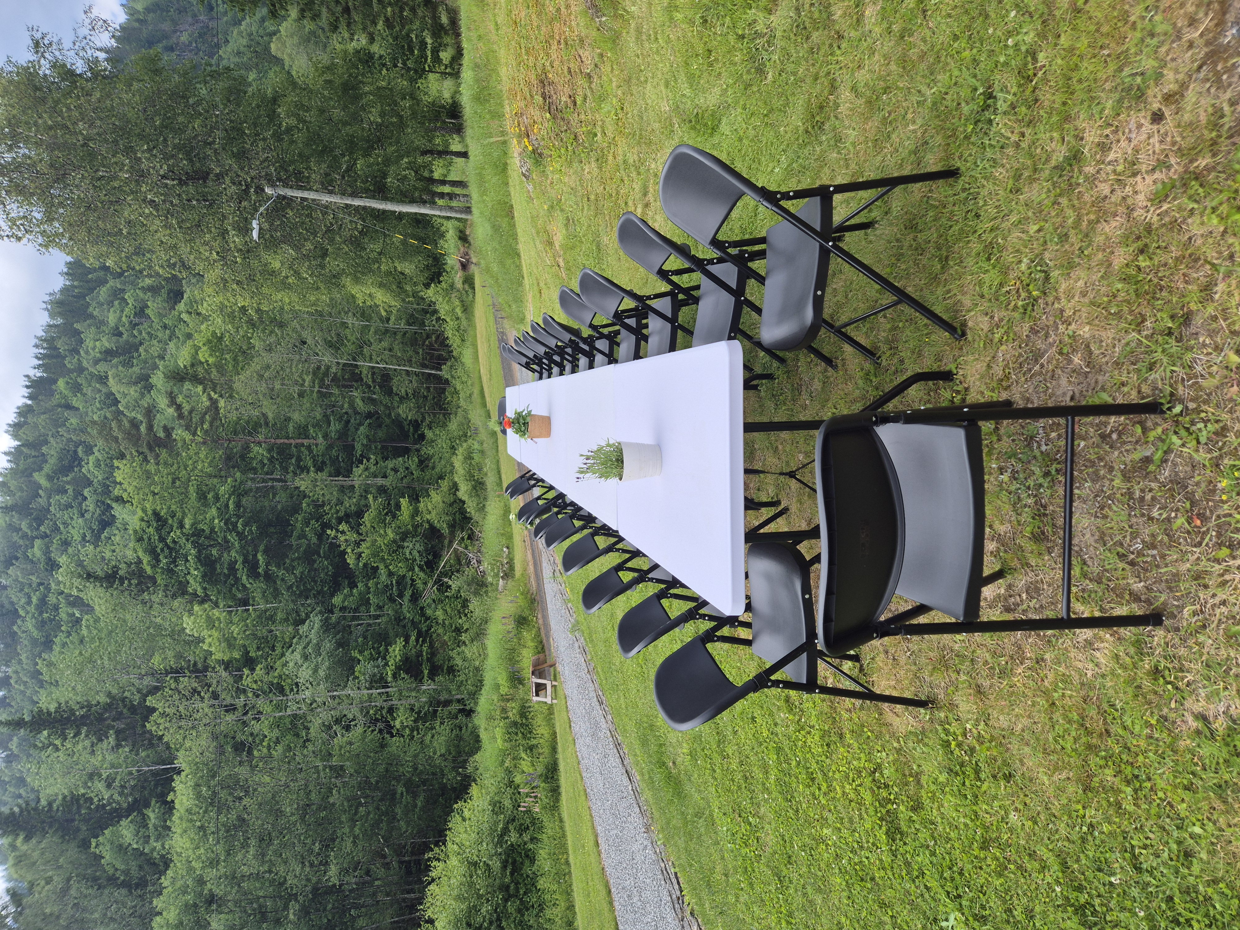 Klappstoler og langbord satt opp på tunet på Nygård